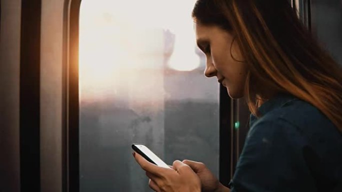 美国芝加哥年轻幸福的女人乘坐地铁的肖像。微笑的女性在日落时使用智能手机