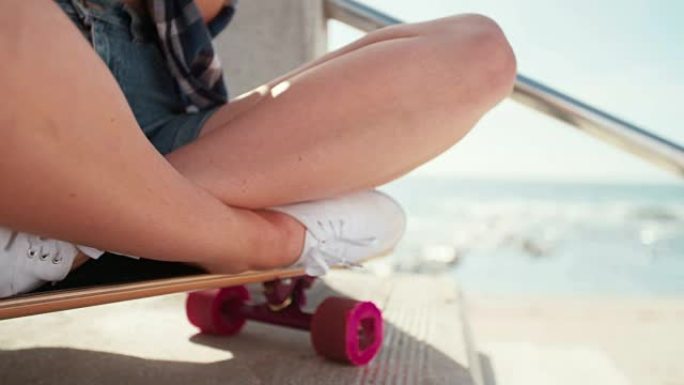 坐在加利福尼亚海滩滑板上的溜冰女孩
