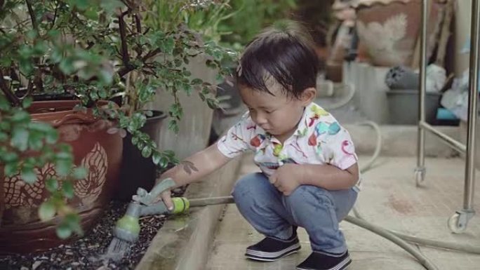 亚洲男婴在家浇灌植物。