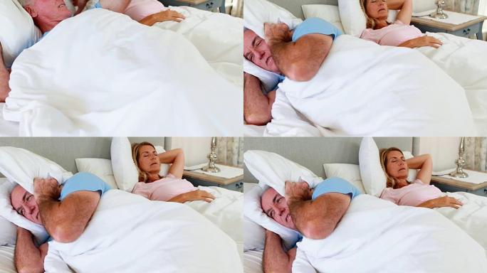 老人躺在床上，用枕头遮住耳朵