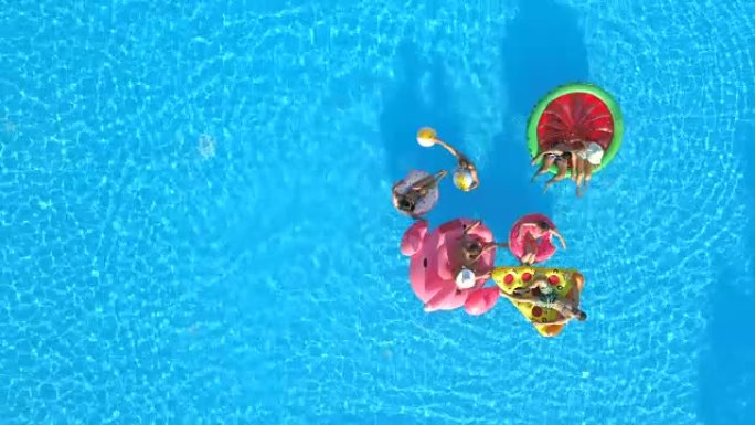 空中快乐的年轻朋友在游泳池里有趣的彩色漂浮物上玩球