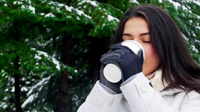 下雪时穿着暖和衣服喝咖啡的女人