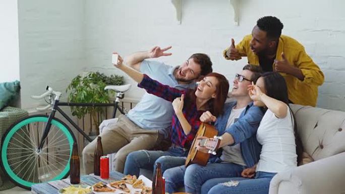 一群快乐的朋友在智能手机相机上拍照，同时在家室内用啤酒和小吃庆祝派对