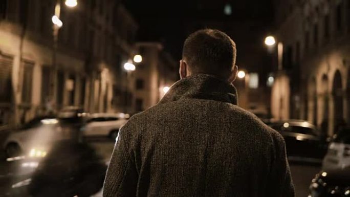 年轻的时尚男人深夜穿过黑暗的街道，晚上独自一人走