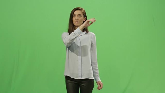 女人正在后台的模拟绿屏上使用虚拟交互界面。