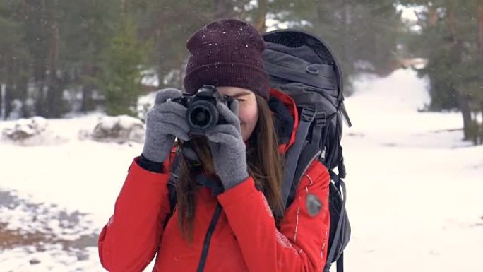 快乐的游客带着照相机在下雪的时候在森林里拍照。