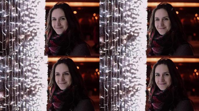 圣诞节之夜，年轻迷人的女人在飘雪中看着背景的相机灯