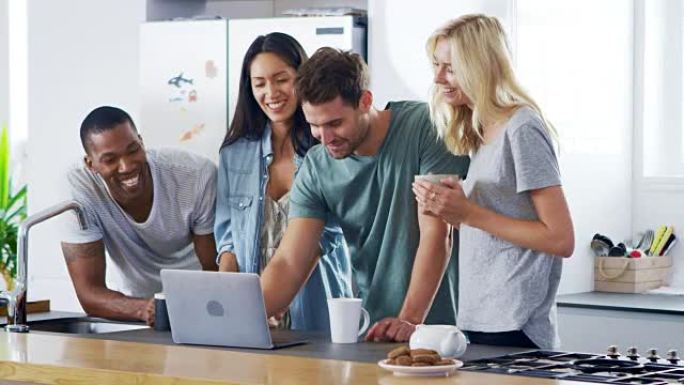 在现代厨房里看着笔记本电脑和喝咖啡的朋友