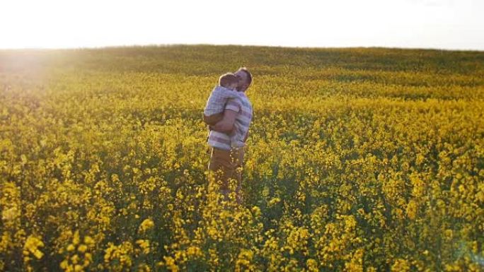 父亲把他的小儿子抱在田野上。慢mo