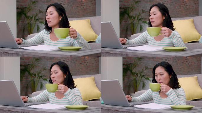 女人在笔记本电脑上打字时喝咖啡