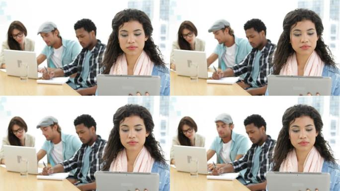 女人在同事背后工作时使用平板电脑