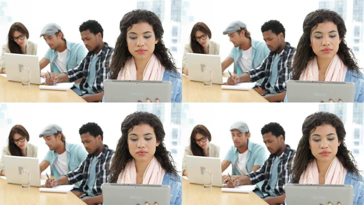 女人在同事背后工作时使用平板电脑