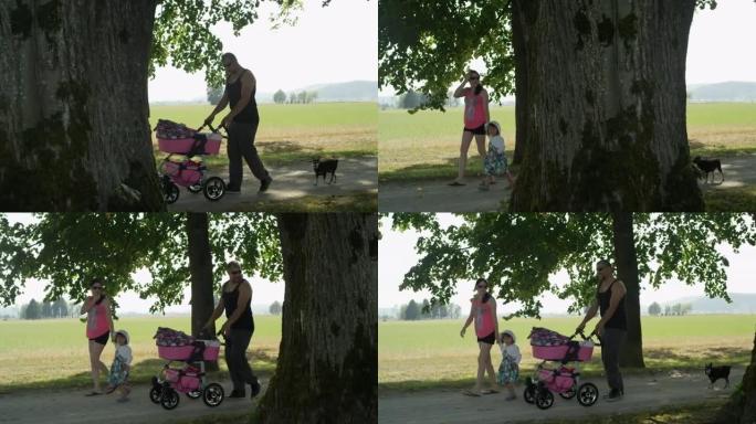 慢动作可爱的年轻四口之家带着他们的狗去阳光明媚的公园散步