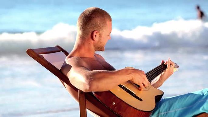男人在沙滩上弹吉他