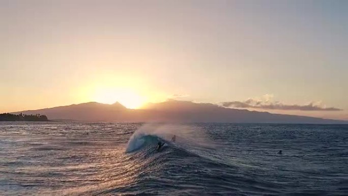 日落时飞越漂浮在海浪中的冲浪者。惊人的日落空中海景