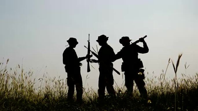战争结束后，三个全副武装的士兵站在战场上的剪影。