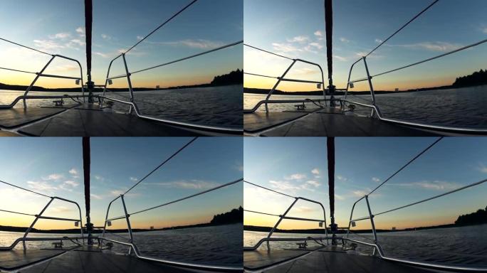 日落时美丽的水景。船的鼻子部分，帆船溅起波浪