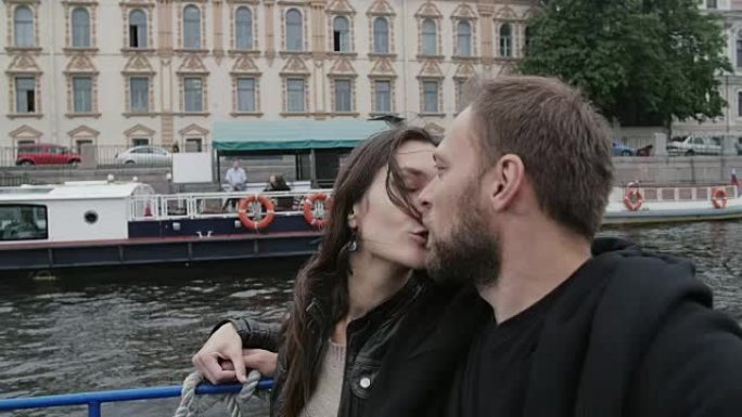 快乐的恋人在河巴士之旅中接吻。圣彼得堡观光。城市建筑，路过码头，慢摩