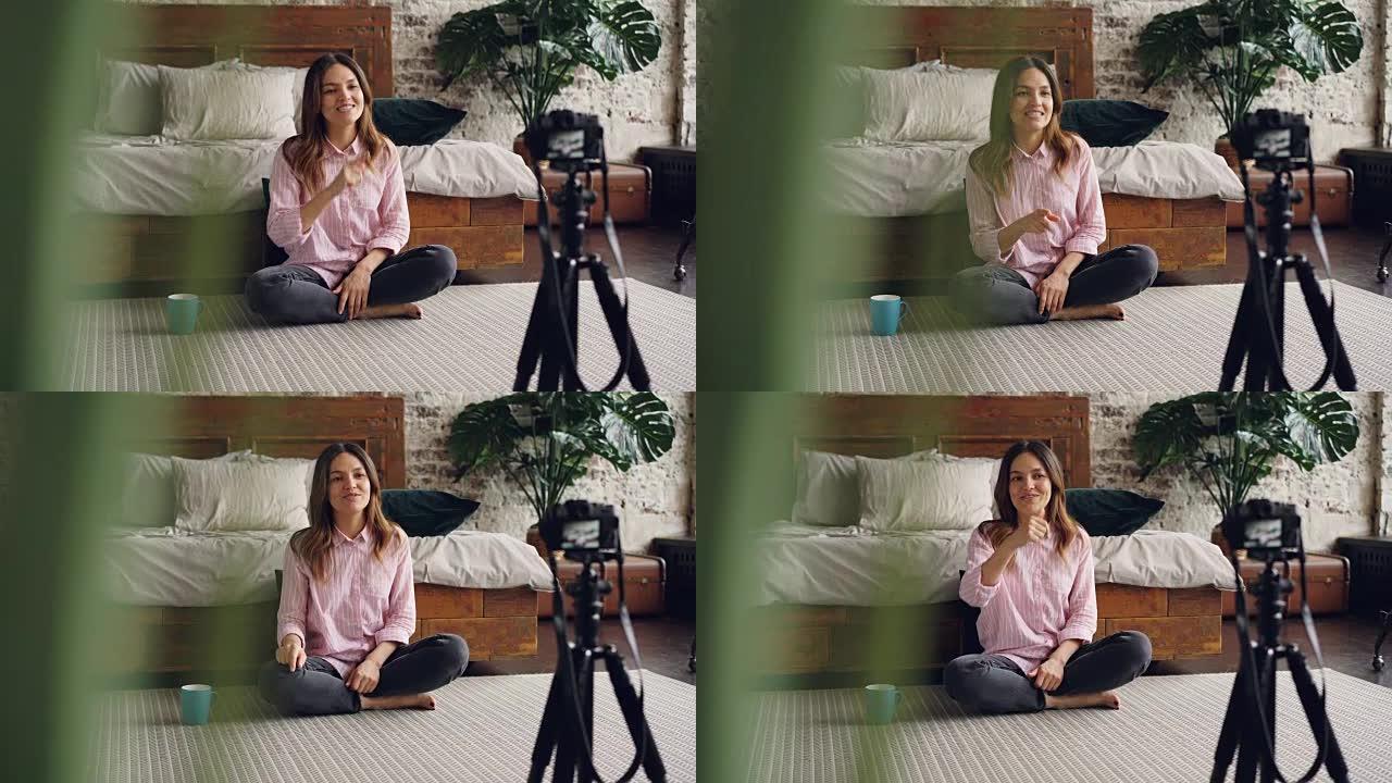 迷人的亚洲女性著名博客作者正在使用相机为她的在线vlog录制视频，她正在说话和打手势，露出竖起大拇指