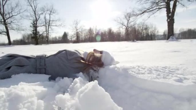 慢动作: 开朗的女人躺下并使雪天使