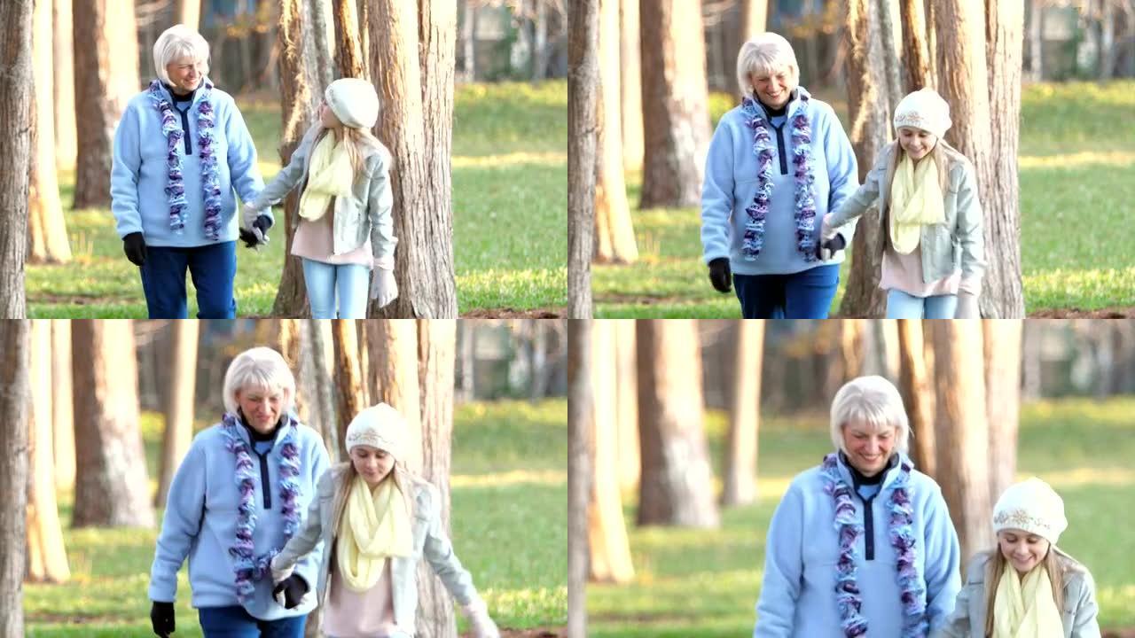 女孩和她的祖母在秋天穿过公园