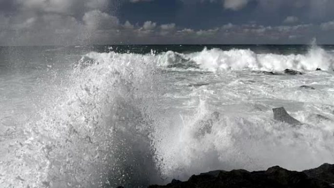 巨浪冲破危险岩石的可怕力量。慢动作镜头