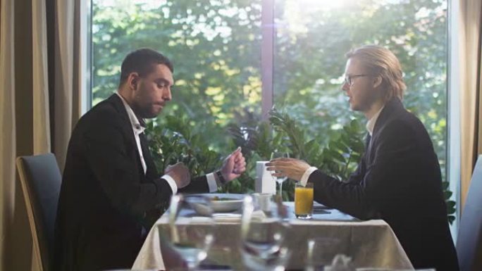 午餐时，两个穿着西装的商人在一家餐馆里交谈。
