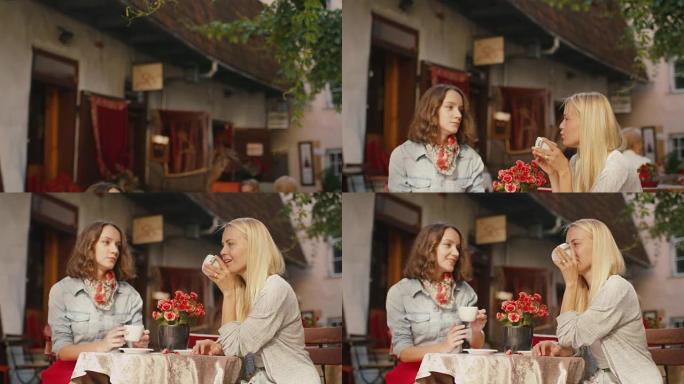 两个快乐的年轻女孩在户外咖啡店喝咖啡