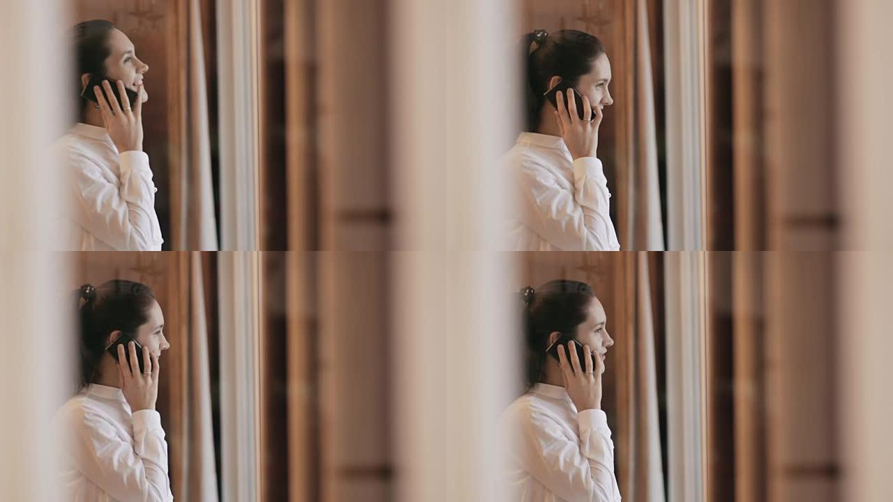 年轻女子在窗户附近的电话上讲话
