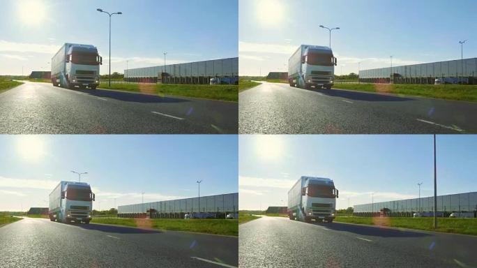 带有货运拖车的白色半卡车在工业仓库区域的空旷道路上移动，背景是阳光普照。