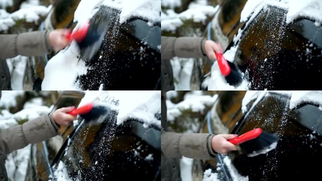 女人的手清除汽车上的积雪