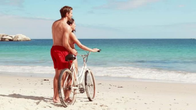 无忧无虑的夫妇在海滩上骑自行车
