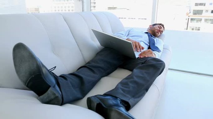 商人用笔记本电脑睡在沙发上