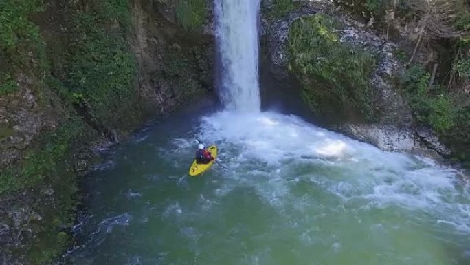 空中: 皮划艇运动员向汹涌的白水瀑布的跳水池划桨