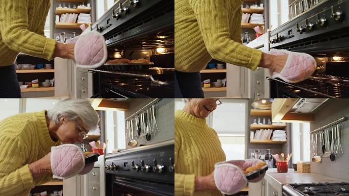 戴烤箱手套的老太太从烤箱中取出新鲜出炉的松饼4K 4k