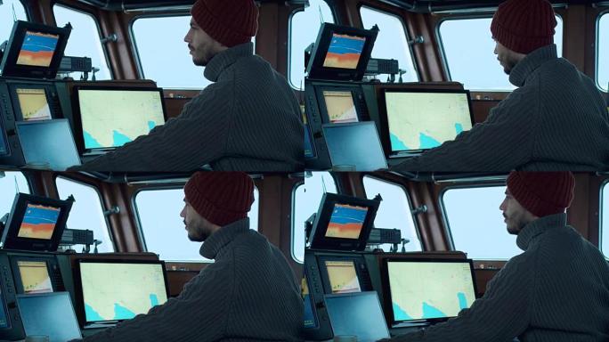 商业渔船的船长在他的船舱里被监视器和屏幕包围着，用海图工作。