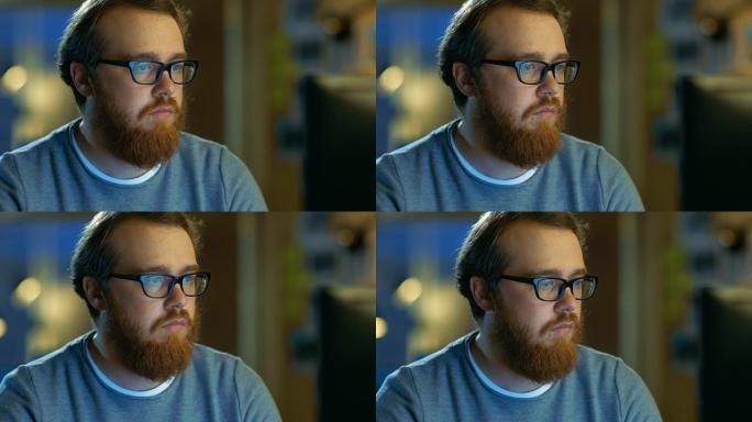 戴着眼镜的年轻大胡子的有创造力的人在个人计算机上工作时会想到一个问题。