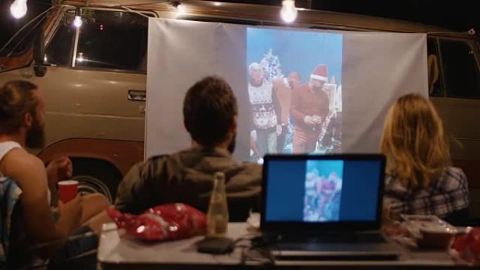 在露营地用投影仪观看视频的朋友