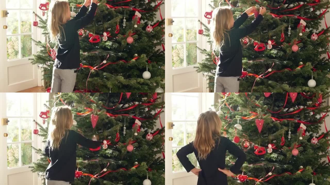 年轻女孩在圣诞树上悬挂装饰品
