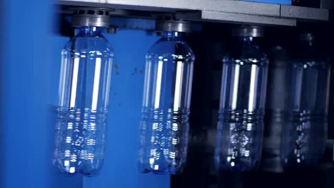 透明的pet瓶瓶坯缓慢移动，后面有发光的光。4K。