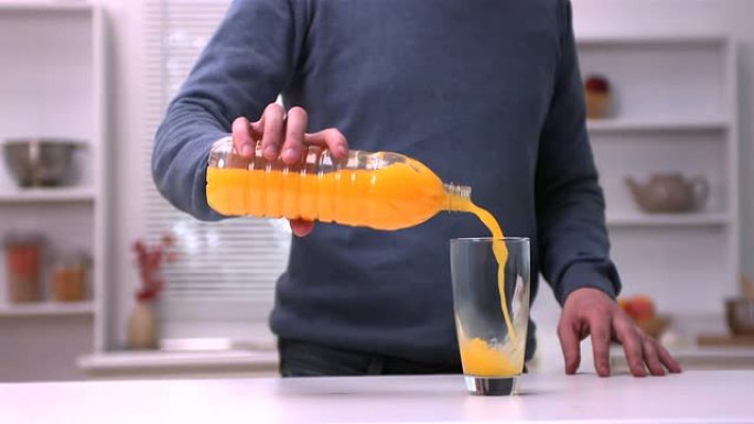 男子将橙汁倒入玻璃杯中