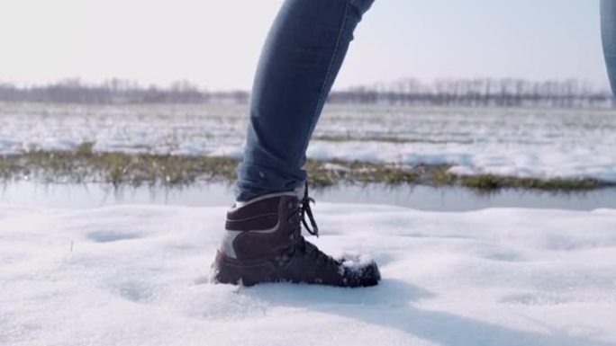 穿着靴子的徒步旅行者在阳光明媚的雪地里行走，超级慢动作