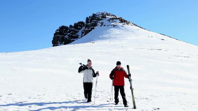 运动情侣沿着滑雪坡行走