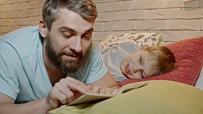 微笑的孩子在床上听爸爸看书