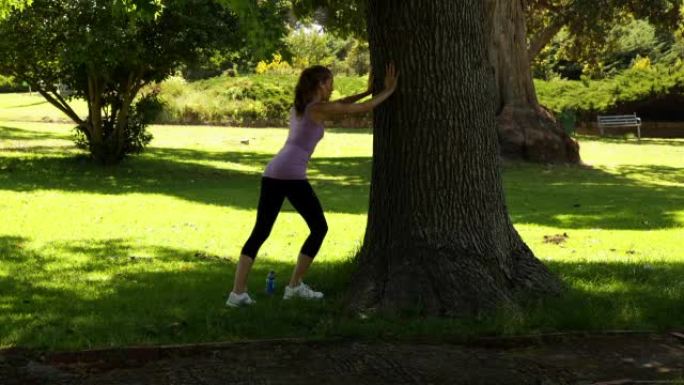跑步者伸腿靠在树上
