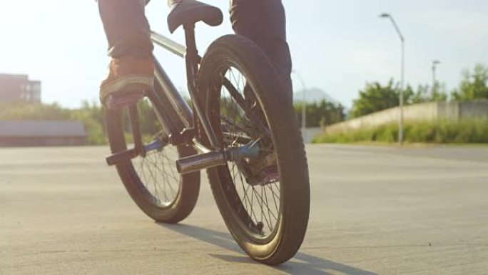 慢动作特写: Bmx骑自行车的人在日落的阳光下做很酷的跳跃技巧