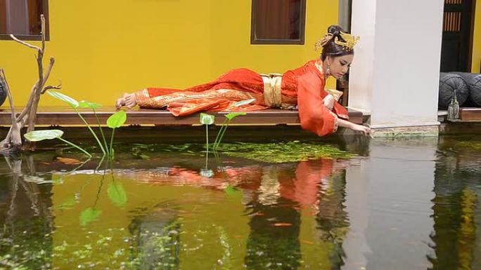 身穿红色格子连衣裙的女人在池塘边放松
