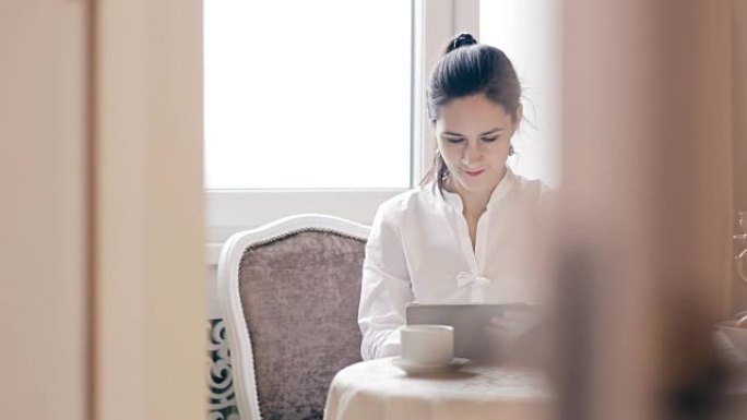 女人使用平板电脑并按桌喝咖啡