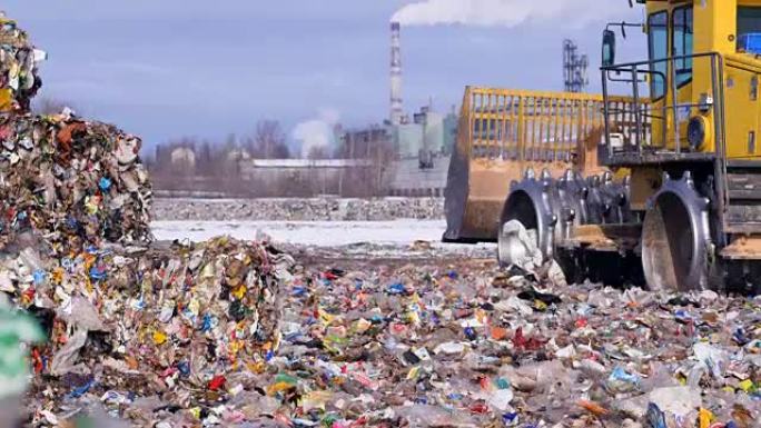环境污染概念。垃圾填埋场拖拉机在成堆的垃圾附近开走。
