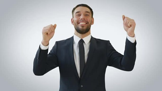 一个微笑的商人举起双手跳舞的镜头。背景是白色的。